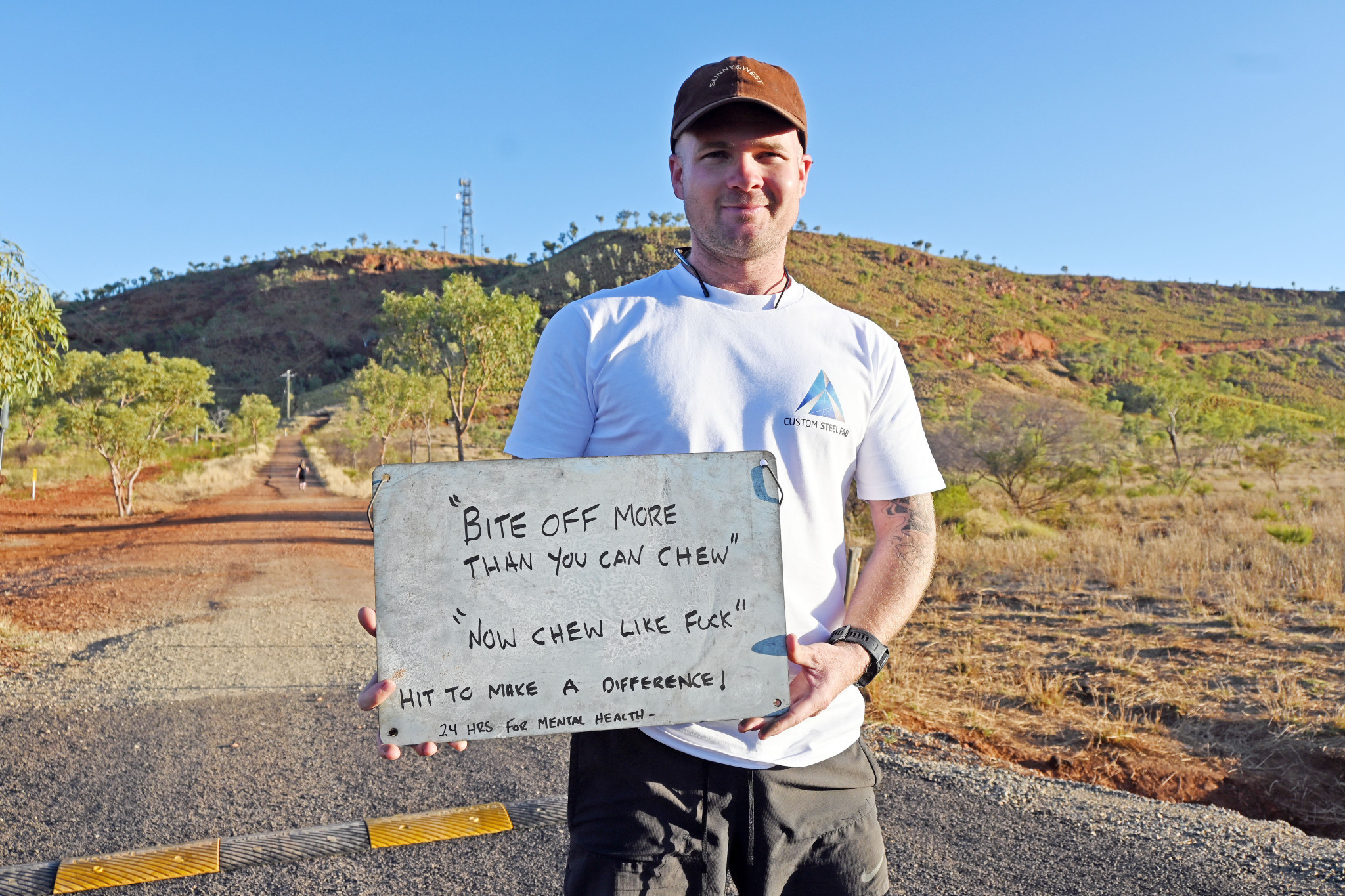 Travis McElligott commenced his journey clutching a sign with an inspirational message that he kept at the top of Telstra Hill to spur him forward for the next 24 hours. He brought the sign back with him on his final loop.